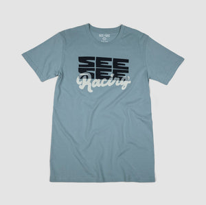 Front shot of light blue adult unisex t-shirt with boxy black See See logo design with the word racing in a white cursive overlay.