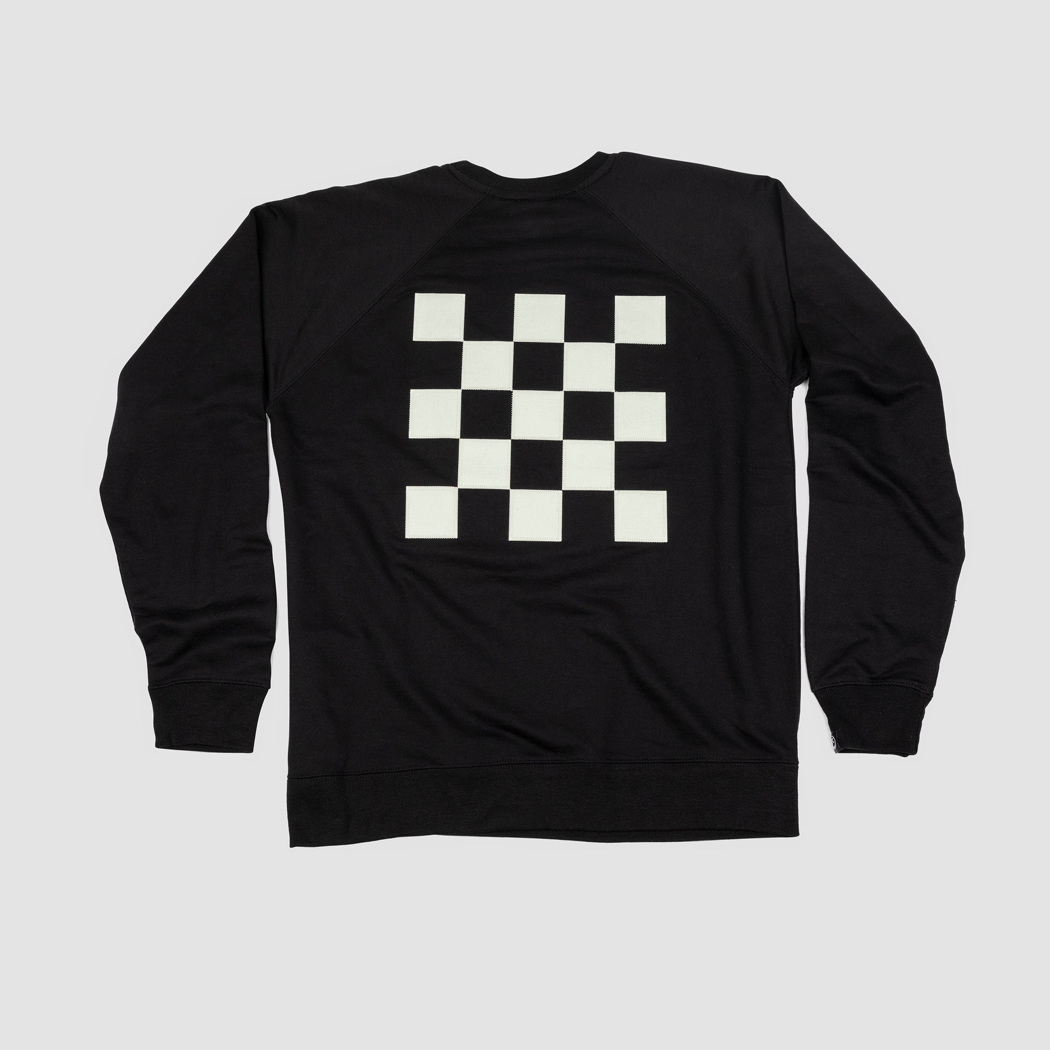 Back shot of black adult unisex premium crew sweatshirt with large centered black and white checkered patch.