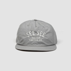Front shot of gray unisex adult surf-style 5-panel hat. Centered text in light gray reads, See See Moto Coffee Co.