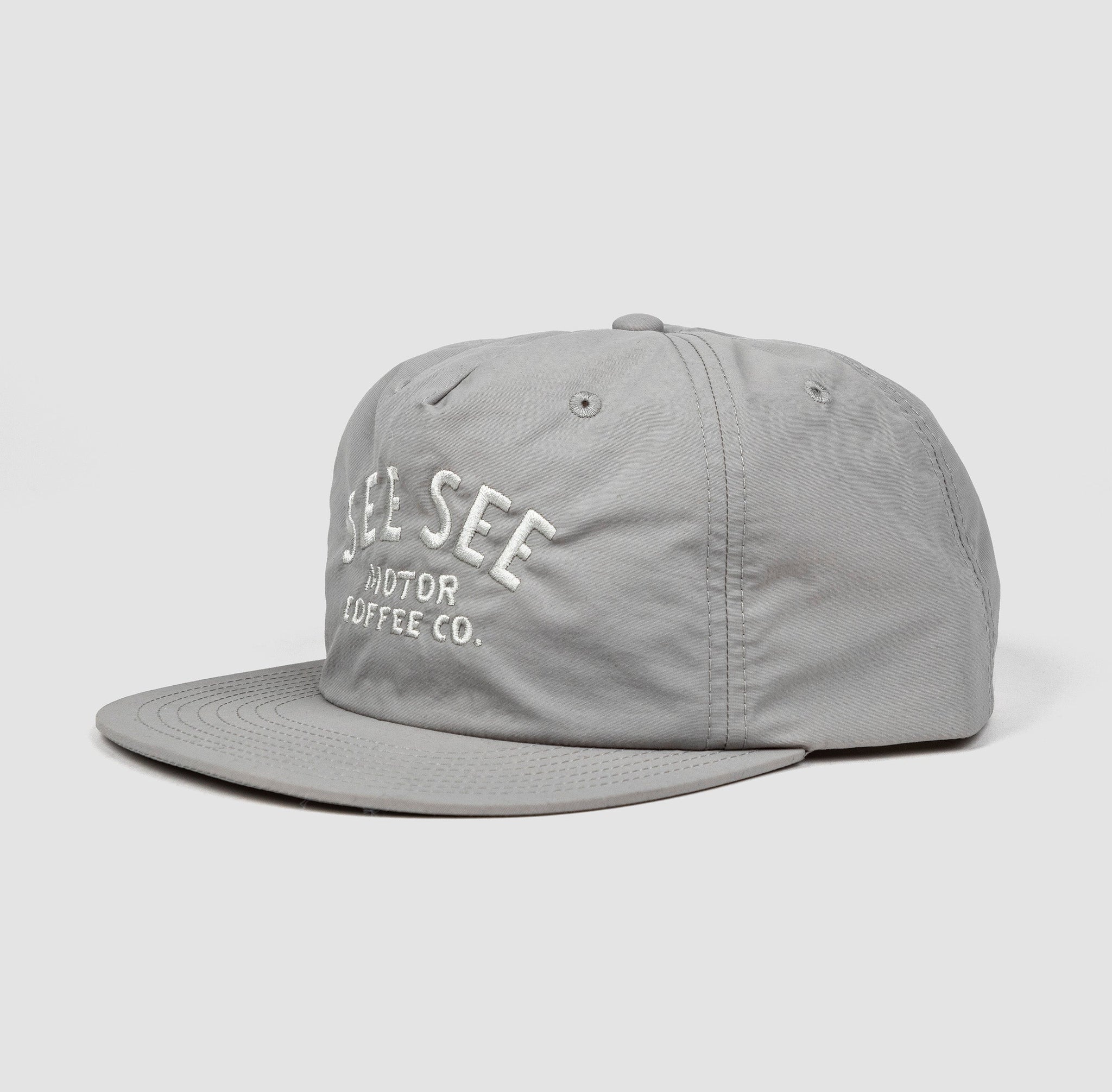 Side angle shot of gray unisex adult surf-style 5-panel hat. Centered text in light gray reads, See See Moto Coffee Co.