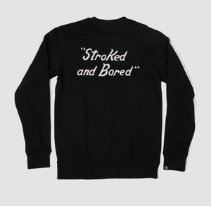 Back shot of black unisex adult premium crew sweatshirt with black embroidered text saying Stoked and Bored.