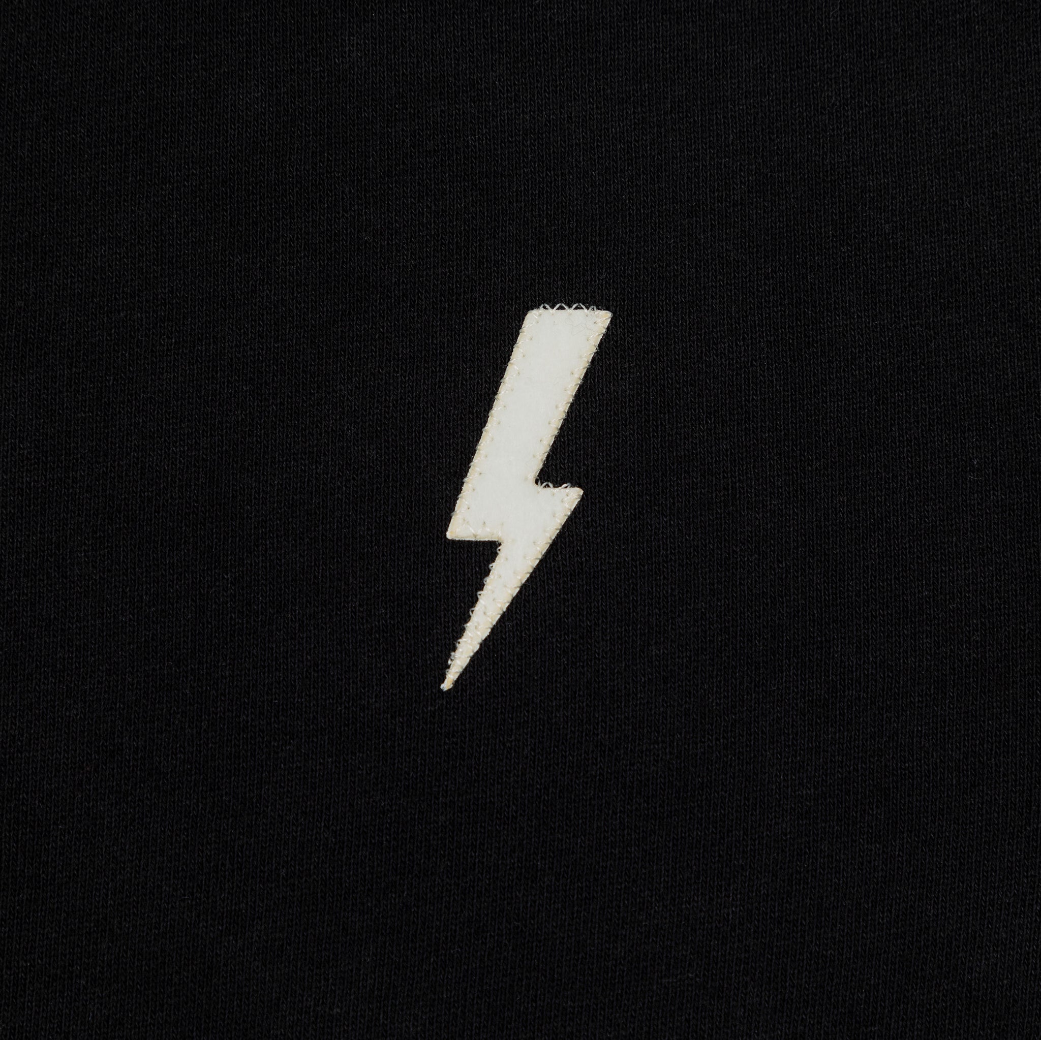 Front detailed shot of embroidered white lightning bolt.