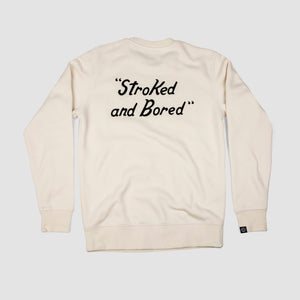 Back shot of bone white unisex adult premium crew sweatshirt with black embroidered text saying Stoked and Bored.