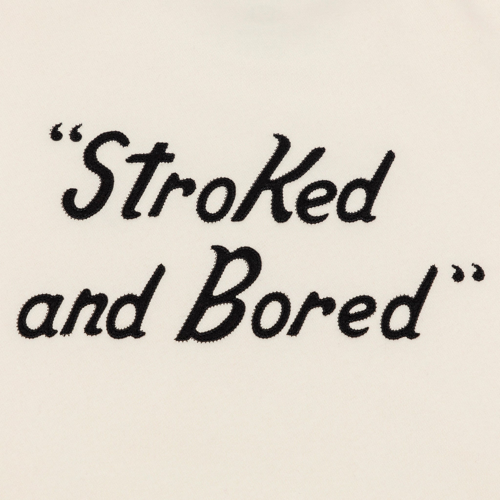 Back detailed shot of embroidered black text saying Stroked and Bored. 